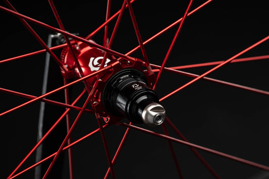 Close-up of a bicycle wheel with red spokes and black hub on a black background