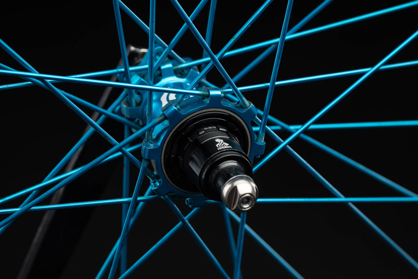 Close-up of a turquoise bicycle wheel hub on a black background