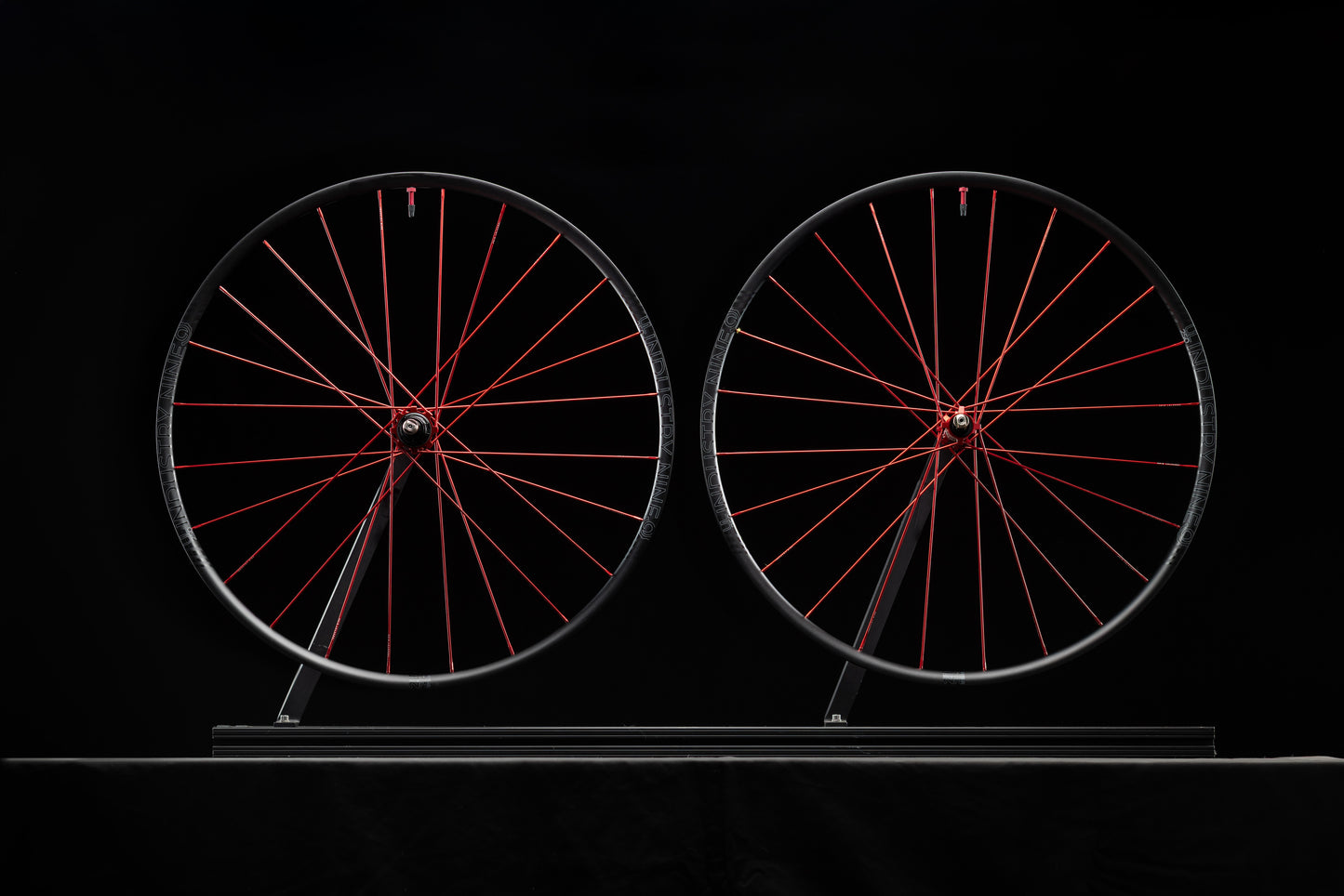 Two bicycle wheels with red spokes on a black background