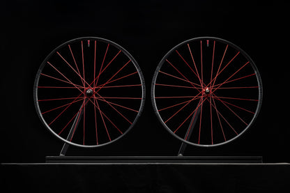Two bicycle wheels with red spokes on a black background