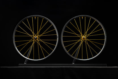 Two bicycle wheels with gold spokes on a black background
