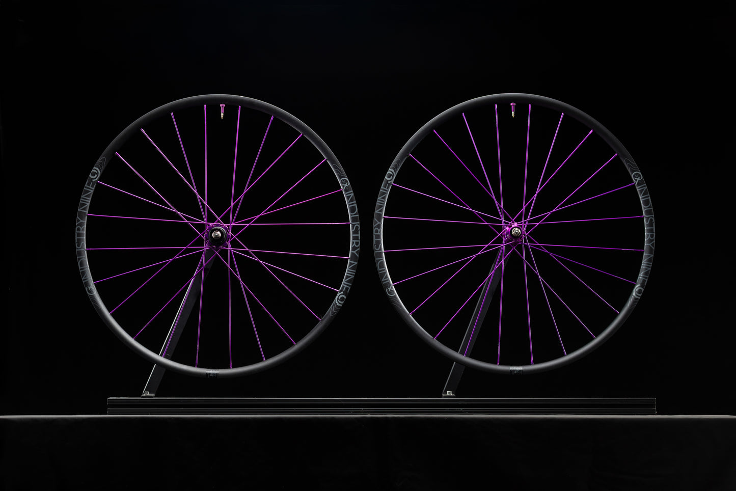 Two bicycle wheels with purple spokes on a black background