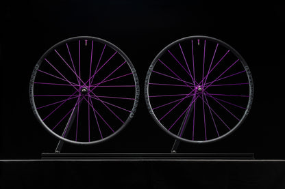 Two bicycle wheels with purple spokes on a black background