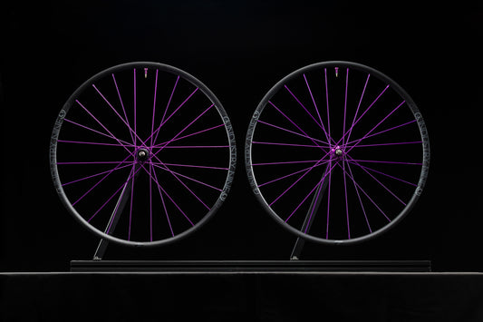 Two bicycle wheels with purple spokes on a black background