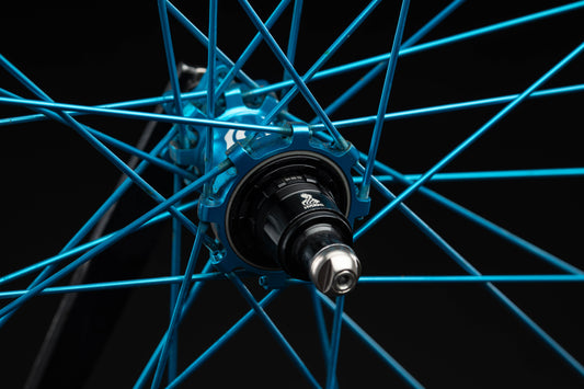 Close-up of a turquoise bicycle wheel hub on a black background