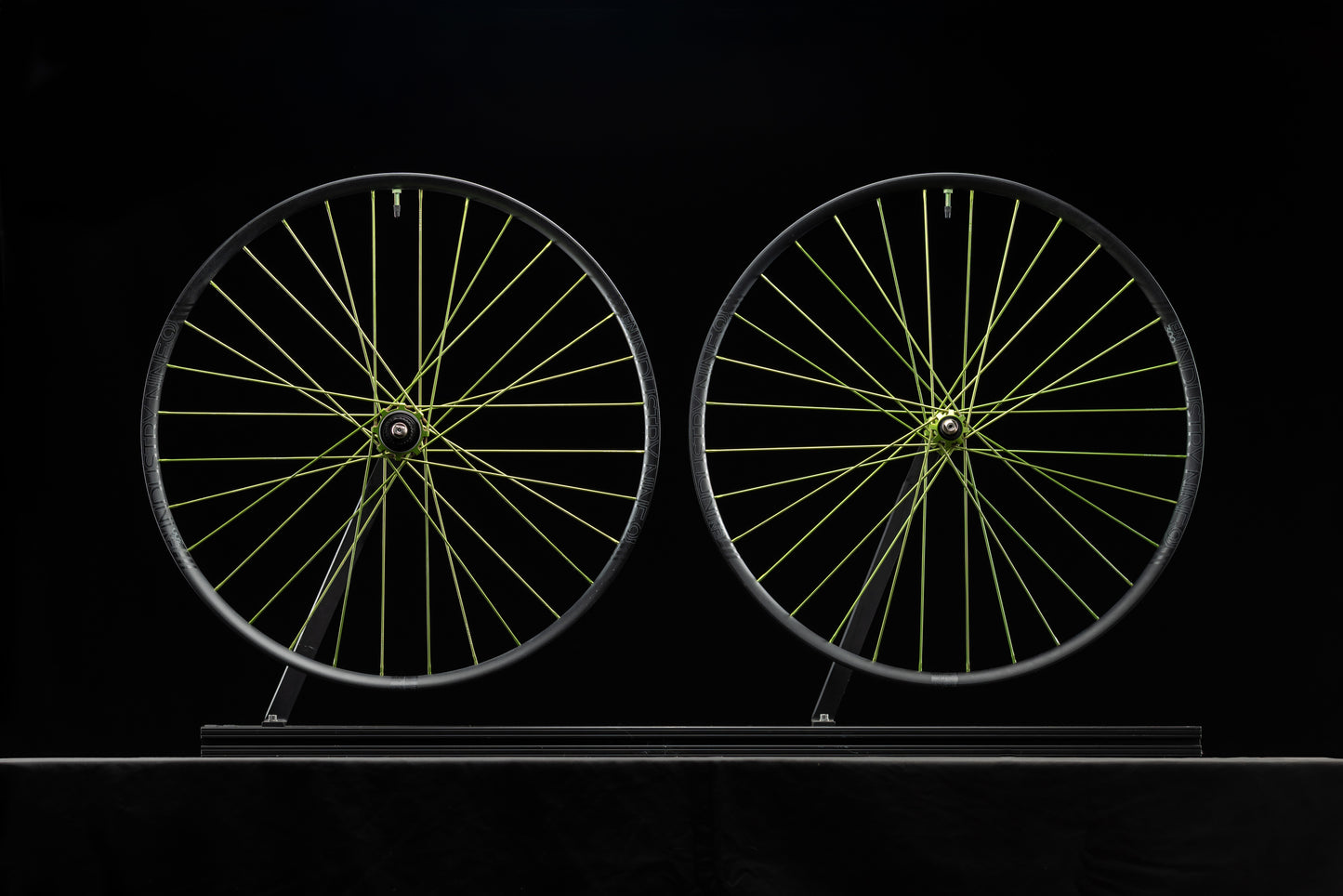 Two bicycle wheels with lime spokes on a black background