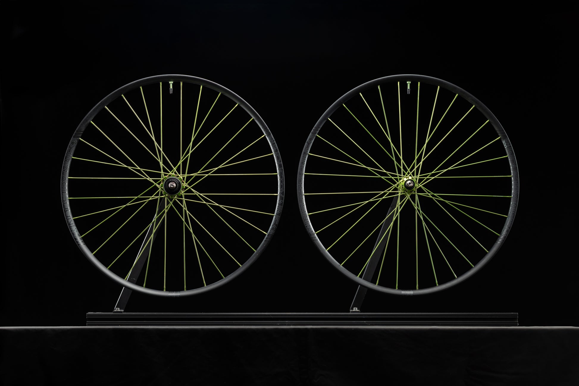Two bicycle wheels with lime spokes on a black background