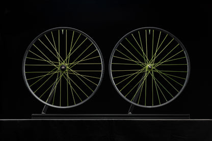 Two bicycle wheels with lime spokes on a black background