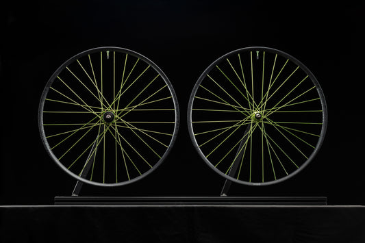 Two bicycle wheels with lime spokes on a black background