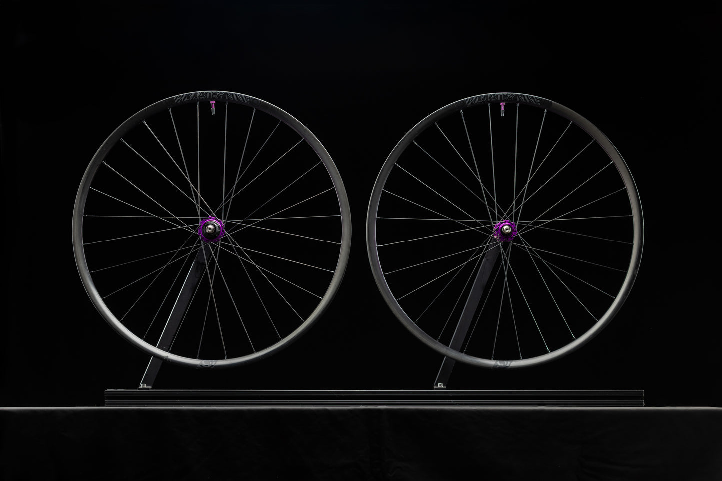 Two bicycle wheels with purple hub on a black background