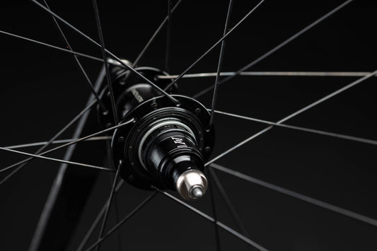Close-up of a bicycle hub with spokes against a black background